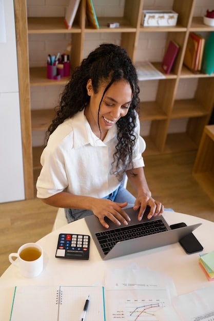 A person sitting at a desk, using a calculator and looking at a tax form, representing the process of calculating tax benefits related to voluntary pension savings in Colombia.